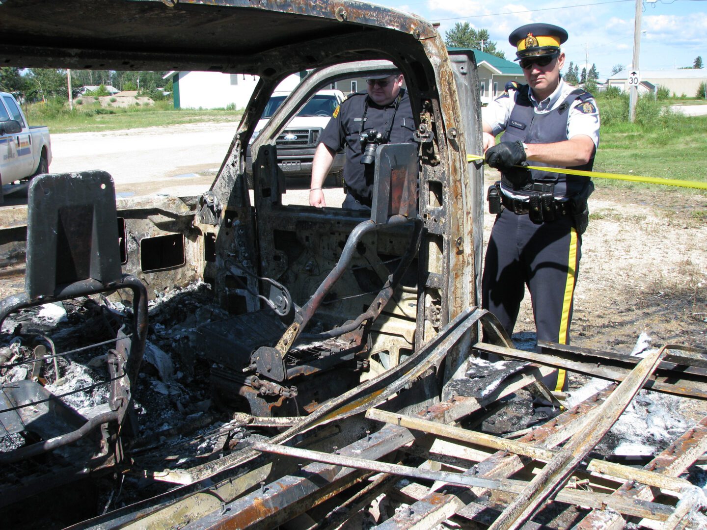 A police officer is looking at the remains of an old car.